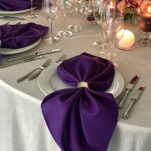 Violetinės spalvos stalo servetėlė 50x50cm. Nuomos kaina 0,5 €.